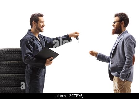 Mécanicien automobile donnant la clé d'une voiture à un homme barbu isolé sur fond blanc Banque D'Images