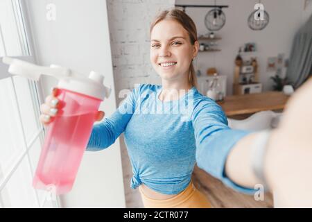 Selfie photo jeune femme athlète avec bouteille d'eau. Concept sport en ligne blogger influenceur home Banque D'Images