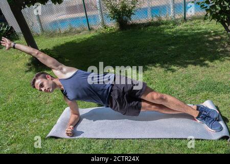 adolescent effectuant des exercices de poussée pour renforcer les muscles dans le jardin Banque D'Images