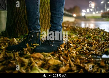 Image conceptuelle des pieds des femmes en chaussures bleues sur les feuilles d'automne. Pieds, chaussures, randonnée dans la nature Banque D'Images