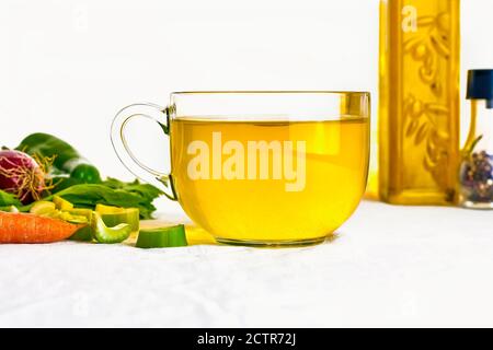 Délicieux bouillon de légumes transparent fait maison dans la tasse en verre sur table blanche. Concept de nourriture saine zéro wast. Banque D'Images