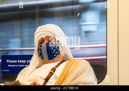 LONDRES, ANGLETERRE - 6 JUILLET 2020 : homme âgé à cheveux blancs portant un foulard arabe keffiyeh et un masque facial sur le métro de Londres pendant le COV Banque D'Images