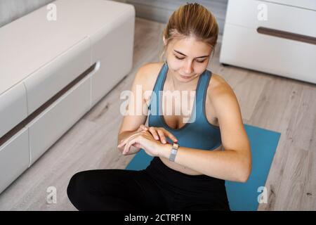 Portrait d'une jeune femme qui vérifie le tracker d'activité numérique pendant l'auto-entraînement à la maison Banque D'Images