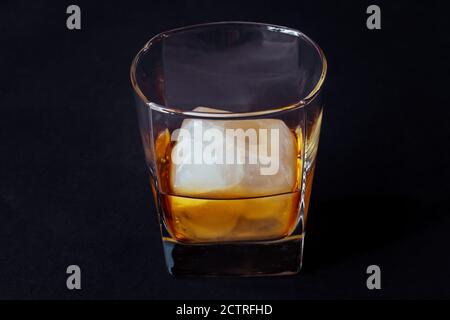 Verre de boisson alcoolisée avec cube de glace sur table noire. Whisky en verre Banque D'Images