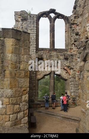 Les visiteurs photographiés se sont mis à admirer les ruines médiévales romantiques de la bibliothèque de l'ancien monastère avec la fenêtre emblématique de la bibliothèque dans le monastère d'Oybin en Saxe, en Allemagne. Banque D'Images