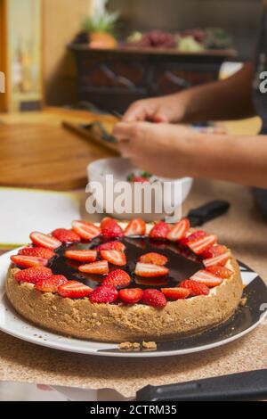 foyer sélectif d'un délicieux cheesecake aux fraises et flou les mains des femmes coupantes les fruits Banque D'Images