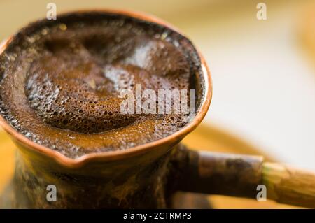 Café naturel avec mousse épaisse, brassé dans une cève de cuivre de la manière classique, sur un fond de bois, photo macro. Banque D'Images
