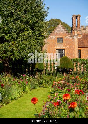 Chenies Manor House Sunken Garden sur un après-midi ensoleillé de septembre 2020. Dahlias colorés, bordures de plantes herbacées, pelouse, treillis d'ivie; ciel bleu. Banque D'Images