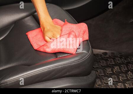 Gros plan d'une femme essuyant l'intérieur de la voiture avec un chiffon rouge. Banque D'Images