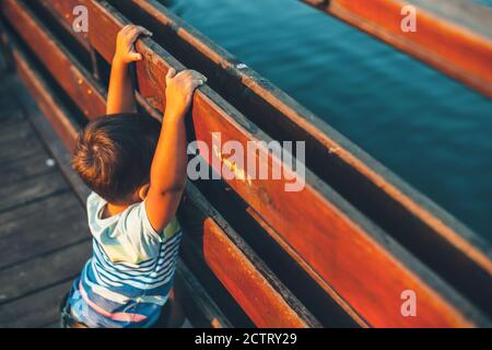 Petit garçon marchant sur le pont et regardant le lac pendant les vacances d'été dans une journée ensoleillée Banque D'Images