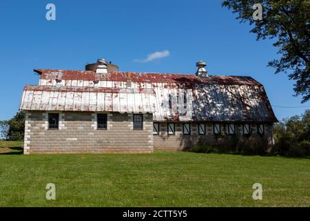 Une ancienne ferme abandonnée avec un grand silo en briques et une grande grange avec un plafond en étain rouillé. Ce très vieux complexe de construction en panne est entouré de gr Banque D'Images