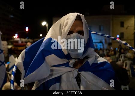 JÉRUSALEM, ISRAËL - 24 SEPTEMBRE 2020 : un manifestant enveloppé du drapeau israélien lors d'une manifestation près de la résidence officielle du Premier ministre dans un cadre de confinement national visant à enrayer la pandémie du coronavirus le 24 septembre 2020 à Jérusalem, en Israël. Une vague de protestations a balayé Israël au cours des derniers mois pour exiger la démission de Netanyahou suite à son inculpation pour corruption et à la gestion de la pandémie du coronavirus. Banque D'Images