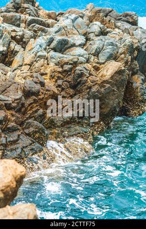 Magnifique décor naturel. Roche en pierre gris brillant brun vif shabby falaise fissures texture montagnes, lazur eau de mer Splash Banque D'Images