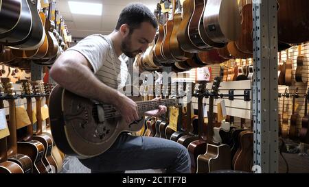Montréal, Québec, Canada - 25 juin 2018 : un heureux acheteur a choisi une guitare dans un magasin de musique. Banque D'Images