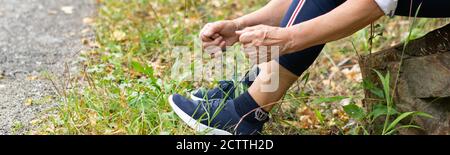 Vue écourtée d'une femme sportive âgée portant des chaussures de sport. Style de vie actif en extérieur Banque D'Images