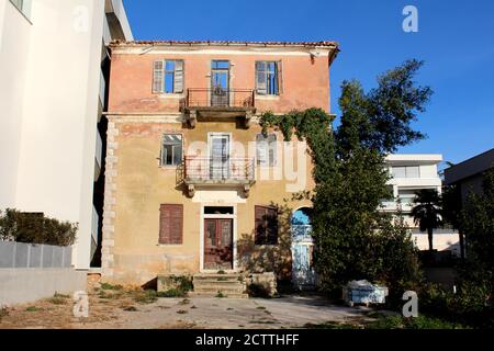 Vieux immeuble d'appartements créepy abandonné avec des fenêtres cassées sur délabré cadres en bois et façade fissurée entourés d'arbres et neufs bâtiments Banque D'Images