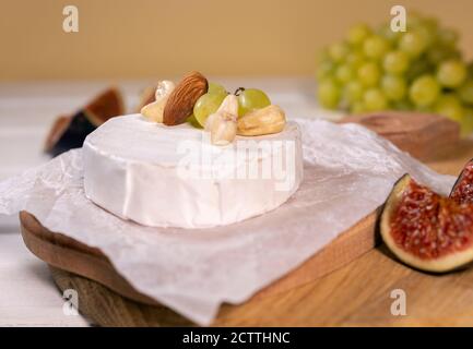 Fromage Camembert sur bois, branche de raisin vert, tranche de figues et noix. Banque D'Images