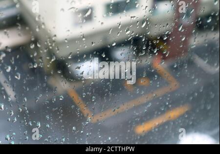 Gros plan sur les gouttes de pluie sur le verre de la fenêtre avec antenne floue vue du parking en arrière-plan Banque D'Images