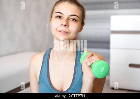 Portrait d'une femme qui tient une haltère en elle mains dans une pièce lumineuse à la maison Banque D'Images