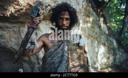 Portrait de Caveman primitif portant une peau d'animal tenant un marteau avec pierre à ébréché. Chasseur de Néandertal préhistorique posant avec la chasse primitive dans le Banque D'Images