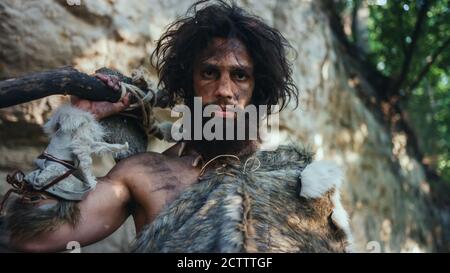 Portrait de Caveman primitif portant une peau d'animal tenant un marteau avec pierre à ébréché. Chasseur de Néandertal préhistorique posant avec la chasse primitive dans le Banque D'Images