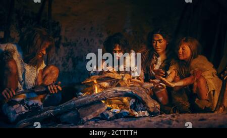 Neanderthal ou Homo Sapiens famille cuisson de la viande animale sur Bonfire et puis la manger. Tribu des chasseurs-cueilleurs préhistoriques portant des peaux d'animaux Banque D'Images