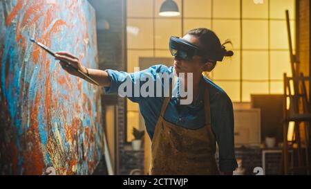 Artiste féminine talentueuse portant un casque de réalité augmentée travaillant sur la peinture abstraite, utilise le pinceau pour créer un nouveau concept d'art en utilisant le virtuel Banque D'Images