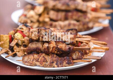 Shish kebab sur des brochettes en bois se trouve sur une plaque arrosée avec des oignons Banque D'Images