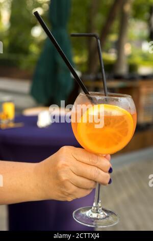 Verre à cocktail avec une tranche d'orange mûr et un tube à boire Banque D'Images