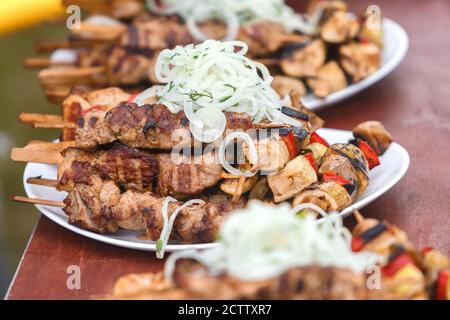 Shish kebab sur des brochettes en bois se trouve sur une plaque arrosée avec des oignons Banque D'Images