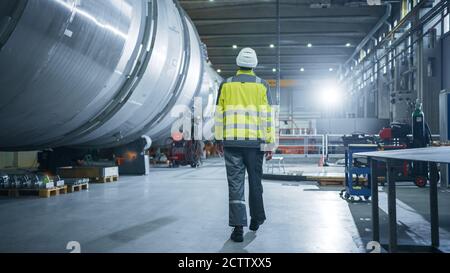 Photo d'un ingénieur de l'industrie lourde qui traverse l'usine de fabrication de tuyaux. Installation moderne pour la conception et la construction de pétrole, gaz et de grand diamètre Banque D'Images