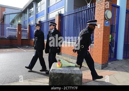 Des policiers marchent à côté de fleurs laissées à l'extérieur du centre de détention de Croydon, dans le sud de Londres, où un policier a été abattu par un homme qui était détenu dans les premières heures de vendredi matin. L'officier a été soigné sur les lieux avant d'être transporté à l'hôpital où il est décédé par la suite. Banque D'Images