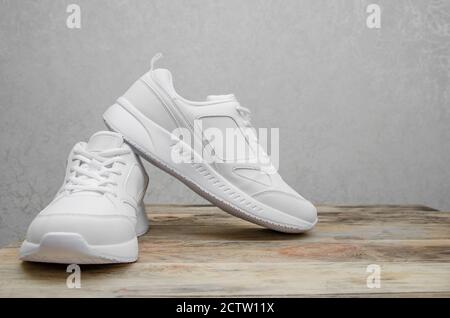 Magnifique paire de nouvelles sneakers blanches pour femme sur un bois gros plan sur l'arrière-plan Banque D'Images
