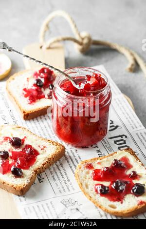 marmelade de pamplemousse avec plateau de baies. Pot de confiture d'orange de sang avec une cuillère en argent et des sandwiches sur le papier sur le plateau de service en bois Banque D'Images