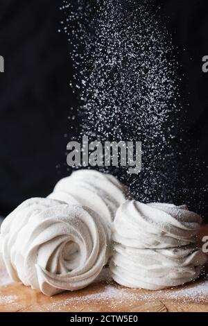 Le processus de fabrication du guimauve zephyr à la cuisine du magasin de pâtisserie. Guimauve blanche maison en poudre de sucre sur fond de bois. Photographie alimentaire. Banque D'Images