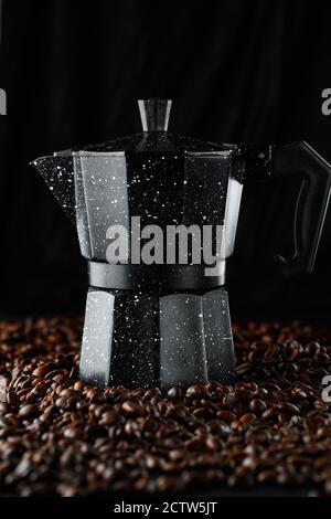 Grains de café noirs en studio. Cafetière geyser sur fond de grains de café fraîchement torréfiés Banque D'Images