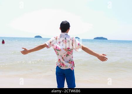 Un homme solitaire se tient sur la plage et regarde vers le soleil léger Banque D'Images