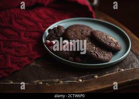 Biscuits au chocolat avec cerises congelées sur l'assiette. Dark and Moody, Mystic Light photographie alimentaire. Banque D'Images