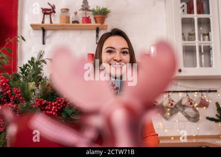 Une jeune fille se cache derrière les bois de cerf La cuisine est décorée avec la décoration du nouvel an Banque D'Images