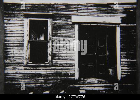 Belle photographie noir et blanc vintage des années 1970 de la porte d'entrée d'une cabane rustique en rondins quelque part dans le désert. Banque D'Images