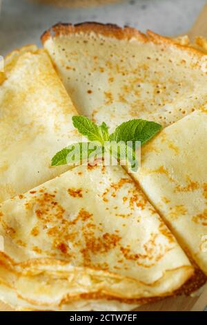 Crêpes russes servies avec des feuilles de menthe et des ingrédients - lait et œufs devant un fond gris. Photographie alimentaire Banque D'Images