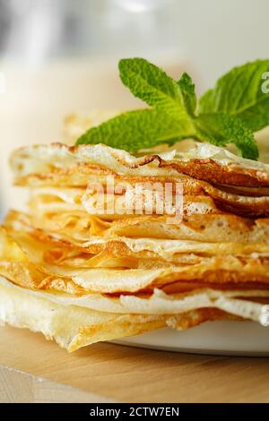 Crêpes russes en gros plan servies avec des feuilles et des ingrédients à la menthe - lait et œufs sur fond gris. Photographie alimentaire Banque D'Images