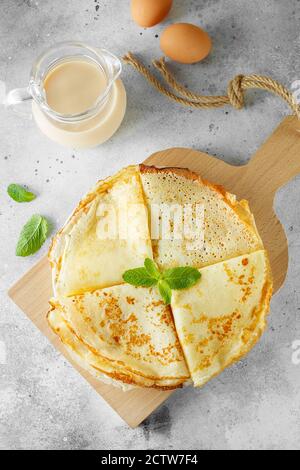 Crêpes russes servies avec des feuilles de menthe et des ingrédients - lait et œufs devant un fond gris. Composition de la pose à plat. Photographie alimentaire Banque D'Images