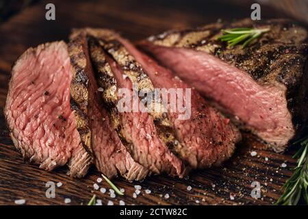 Bœuf moyen juteux entrecôtes de bœuf en tranches de bœuf sur une planche de bois avec épices et sel. Steak prêt à manger avec des ingrédients sur une planche à découper. Banque D'Images