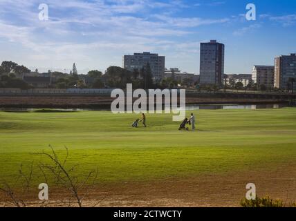 Golfeurs jouant au golf sur une pelouse verte avec un lagon en arrière-plan, le Cap, Afrique du Sud Banque D'Images