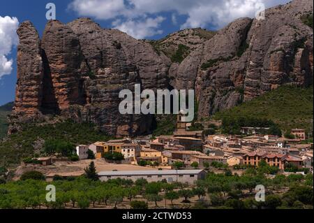 Agüero, un petit village dans les contreforts pyrénéens de Huesca, Aragon, Espagne, s'étend autour d'une belle église romane du XIIIe siècle et se niche sous Los Mallos de Agüero (les maillets ou les Ninepins d'Agüero). Cette formation spectaculaire, également connue sous le nom de collines de Syncline, est constituée de roches de conglomérat d'époque tertiaire teintées de rouge érodées qui s'élèvent jusqu'à 275 mètres (900 pi) au-dessus du peuplement. Banque D'Images