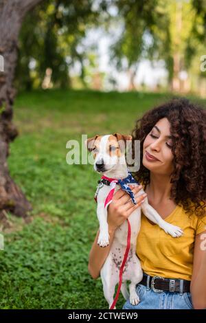 Objectif sélectif de la jeune femme tenant un chien portant le drapeau américain bandana Banque D'Images
