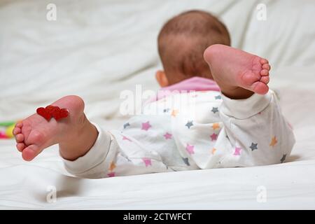 Bébé repose avec les coeurs sur leurs pieds. Un nouveau-né est allongé sur le lit. Banque D'Images