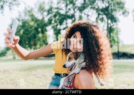 une femme joyeuse qui prend le selfie sur son smartphone avec jack russell terrier chien dans le parc Banque D'Images