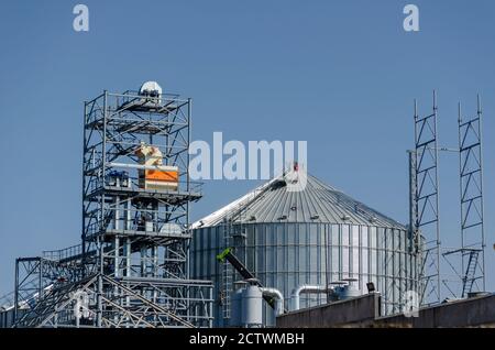 Construction d'un terminal de grain moderne sur fond bleu ciel. Silo cylindrique métallique et structure métallique de support pour le convoyeur de chargement. Distribution Banque D'Images